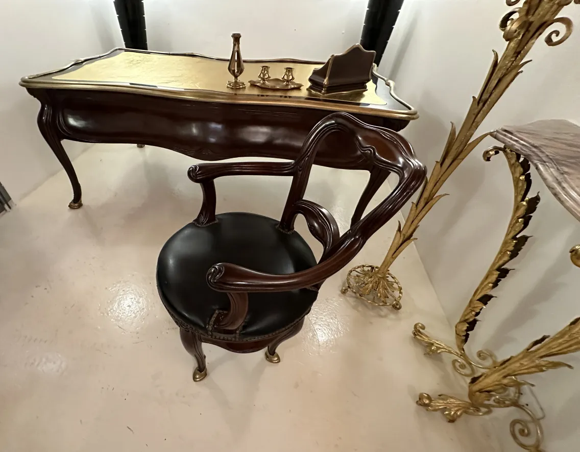 Bureau ancien avec des accents dorés et une chaise élégante.
