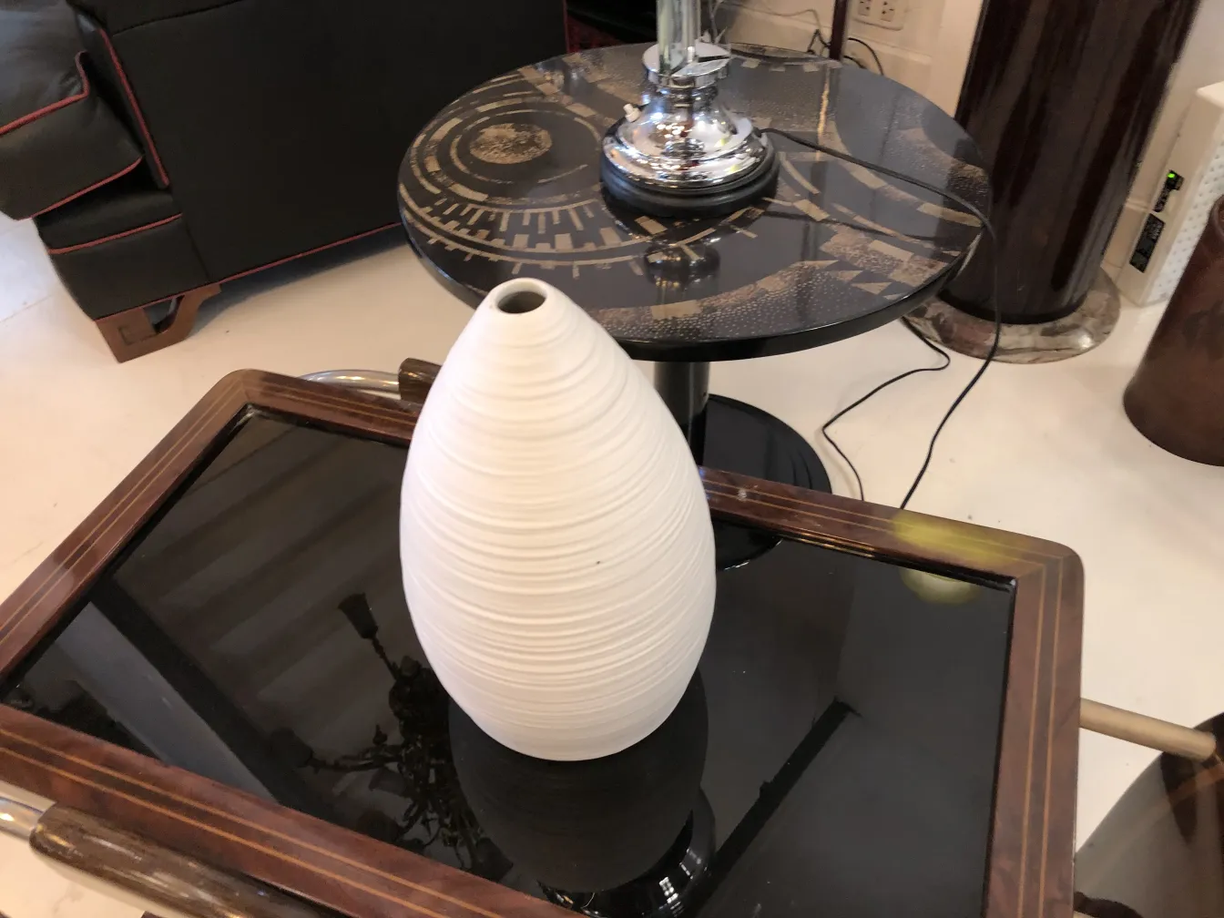 波状テクスチャの白い陶器の花瓶が黒いガラスの上に