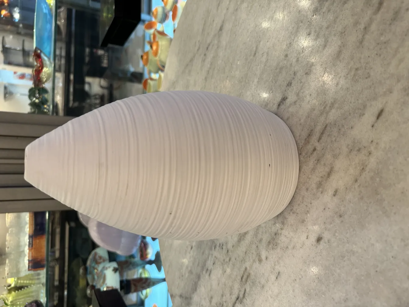 Vase en céramique antique avec design lisse et formes organiques, surface blanche, dans un cadre élégant.