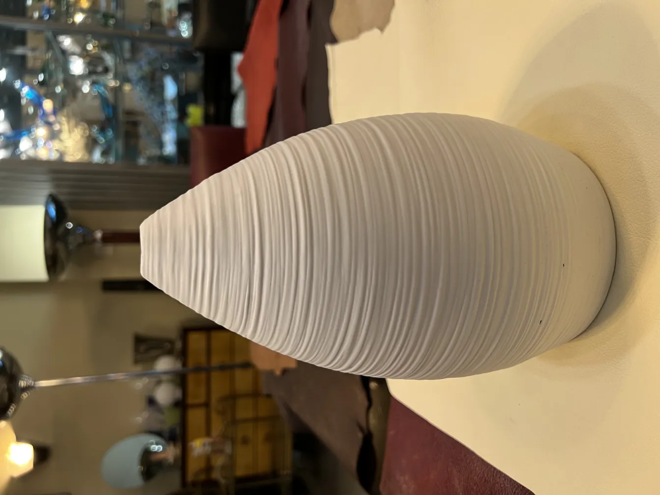 Scultura antica in ceramica bianca con texture ondulata.