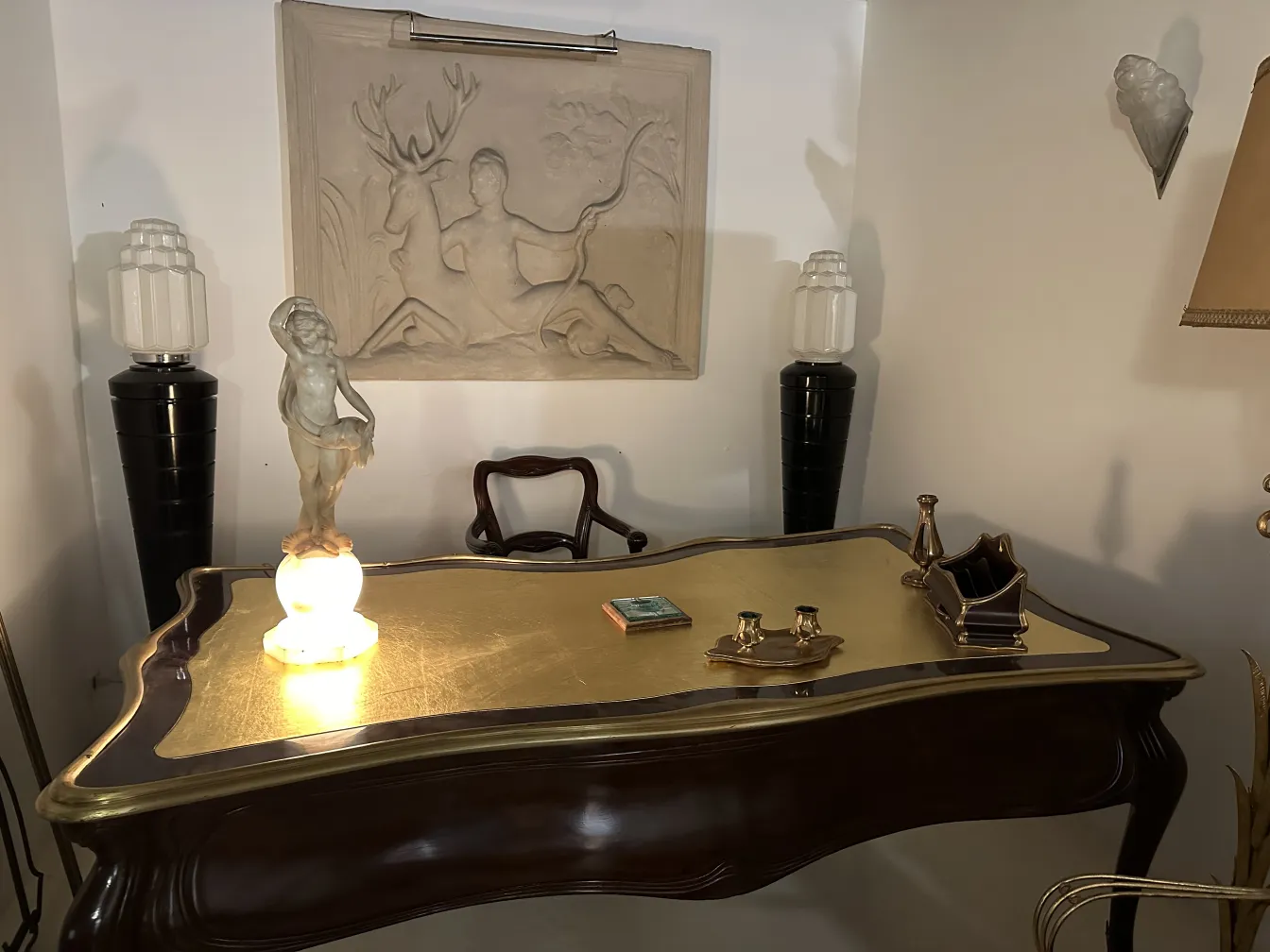 Bureau ancien avec lumière sculptée et objets décoratifs dans un cadre accueillant.