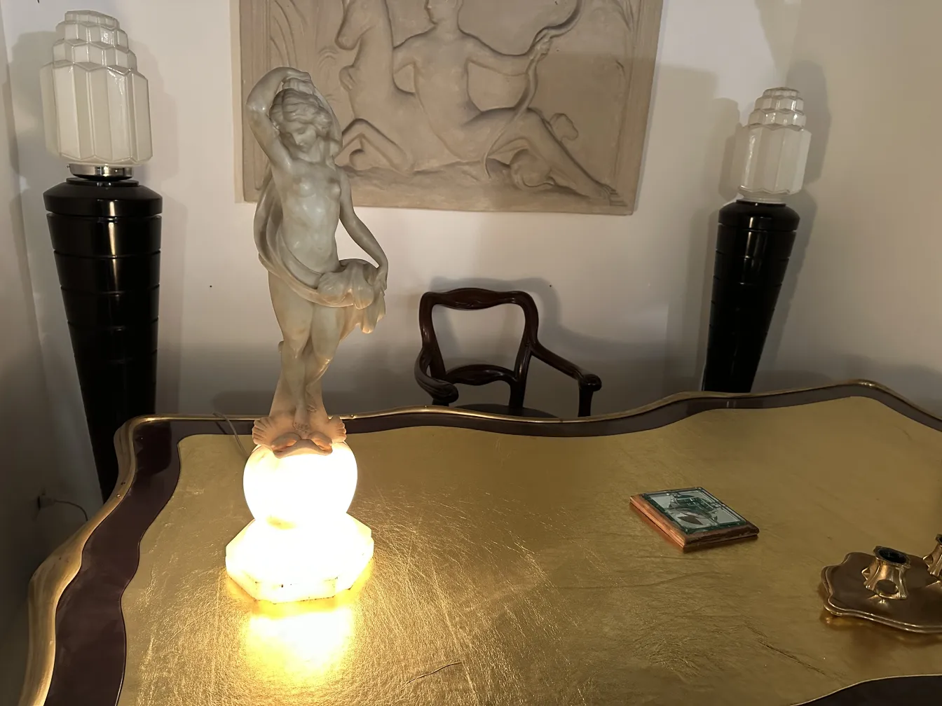 Escritorio antigo dourado com lâmpada decorativa e ornamento.