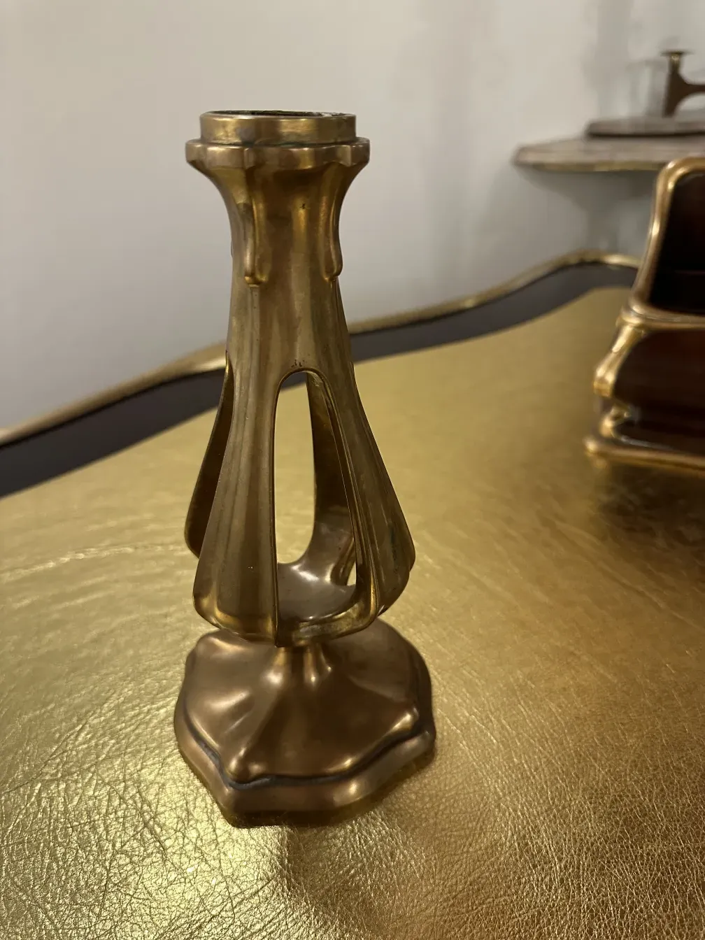 Antique candlestick on a desk in a classic setting.