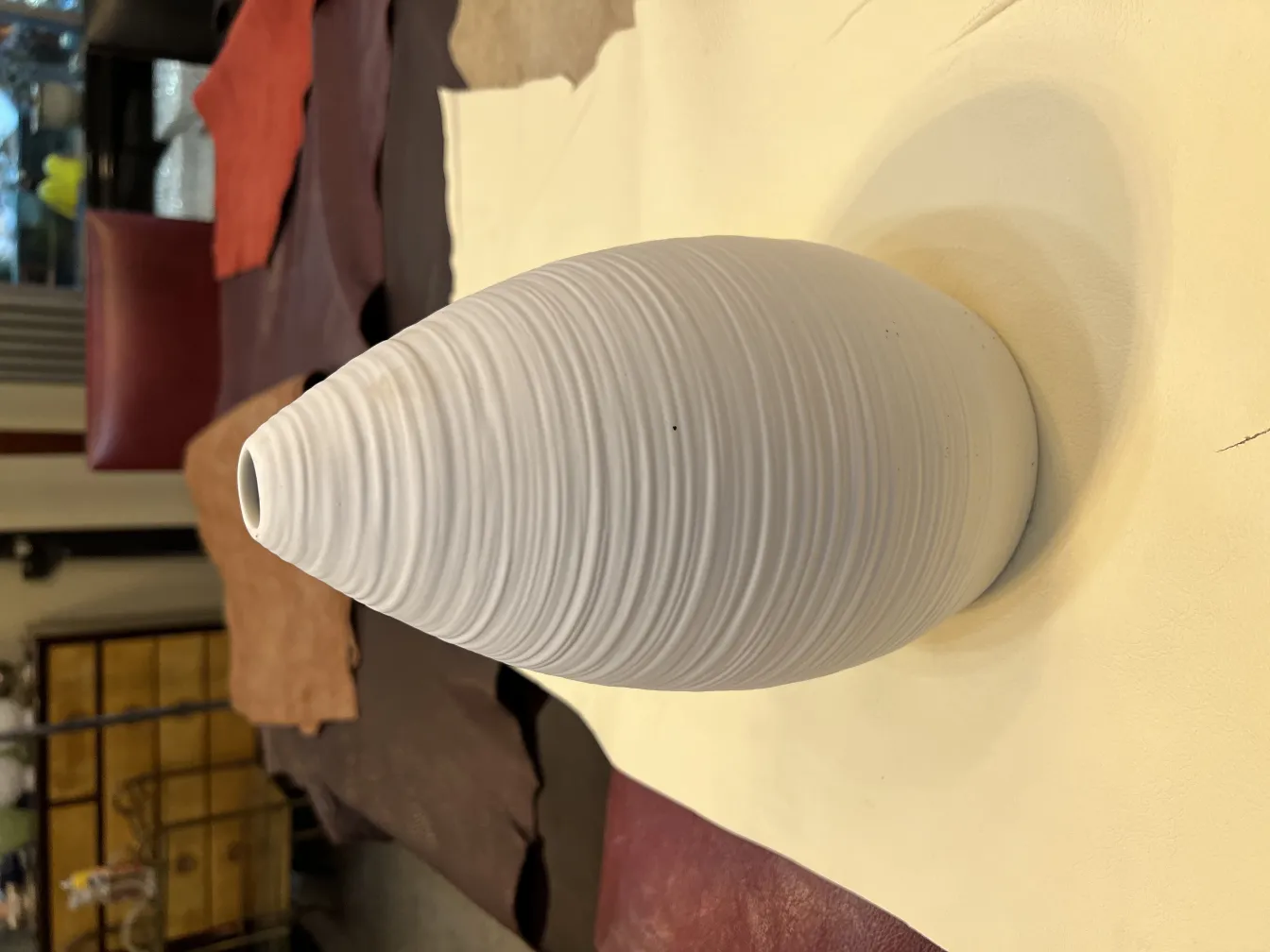 Vaso de cerâmica branca antiga com textura em um fundo de couro.