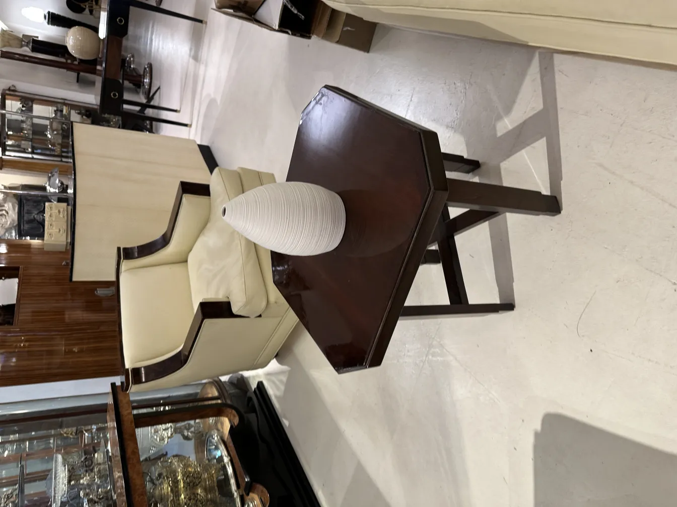 Vase en céramique élégant sur une table en bois, avec une chaise en arrière-plan dans un cadre ancien.