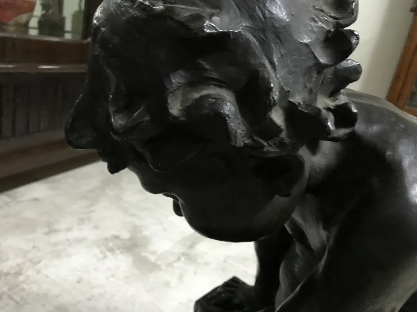 Detail of an antique sculpture with dark finish and nostalgic expression, in a classic setting.