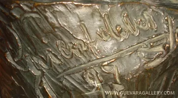 Détail d'une sculpture antique avec signature visible.