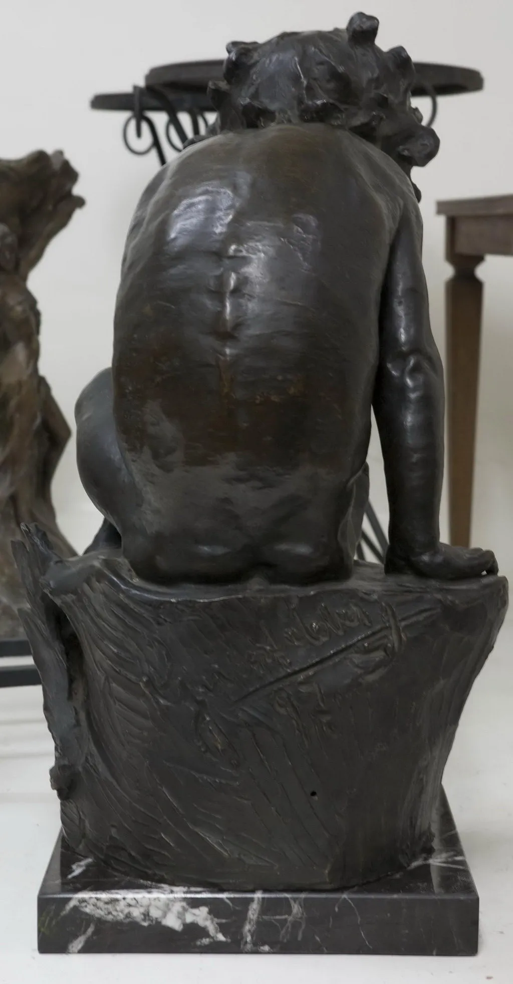 scultura antica di una figura umana vista da dietro, dettagli sulla base