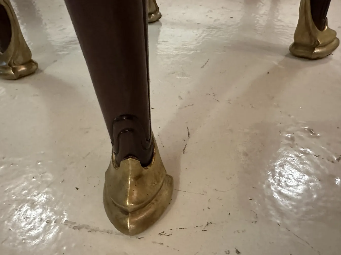 Détail d'une jambe de bureau ancien avec des pieds dorés.