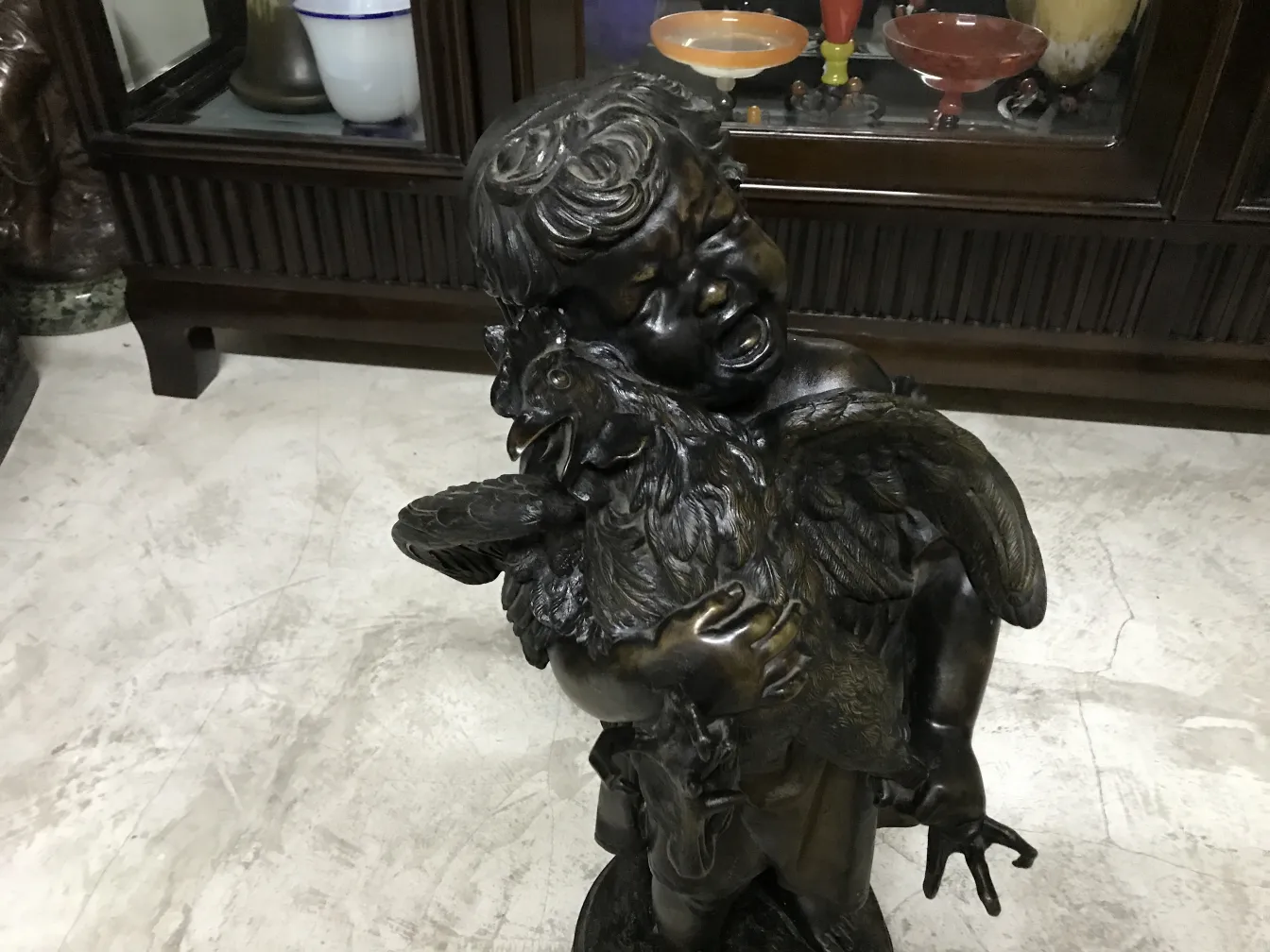 escultura antigua de niño abrazando un gallo en ambiente clásico