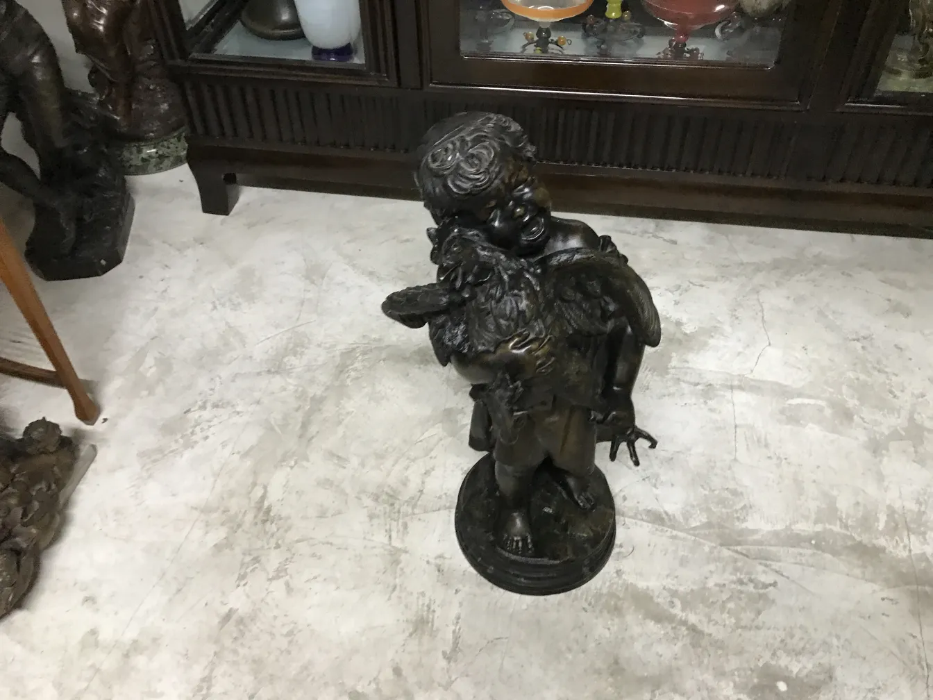 escultura antigua de un niño con alas y un ave, ambiente decorativo