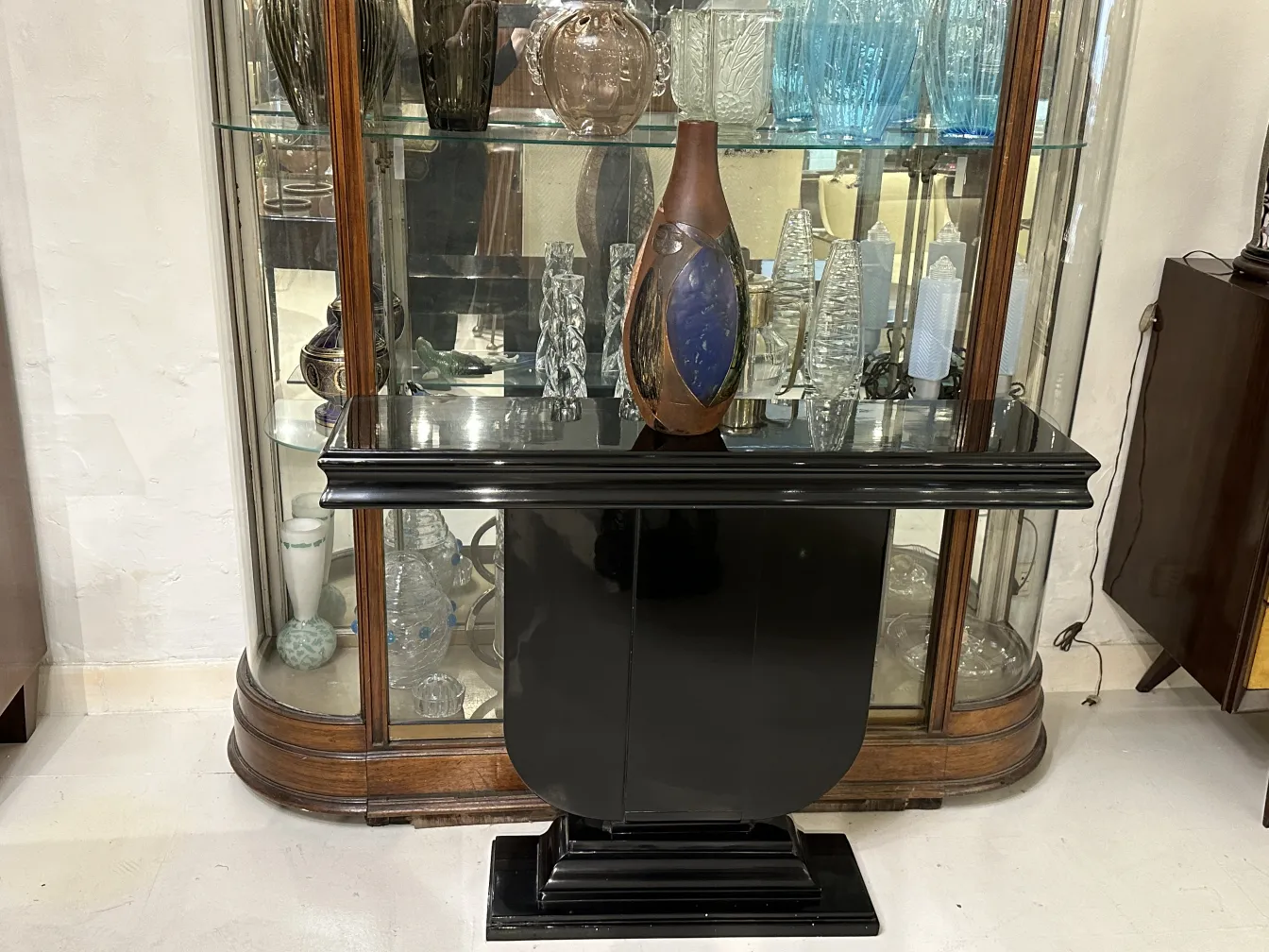 Vase en céramique ancienne avec des formes stylisées, entouré d'objets décoratifs clairs dans un cadre élégant.