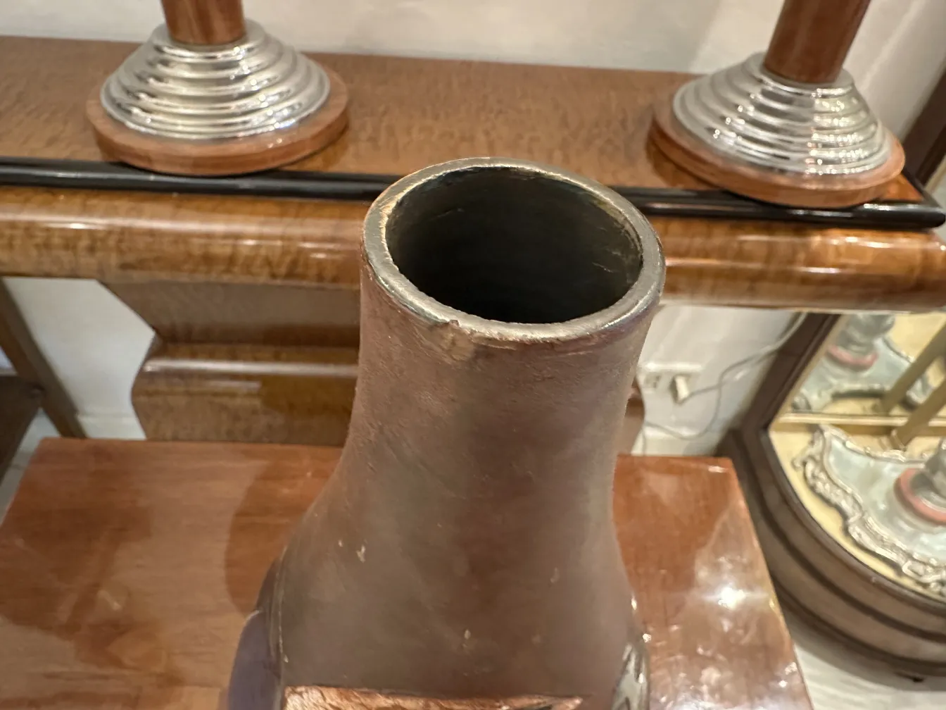 Vaso de cerâmica antiga com acabamento rústico, decorações sutis em um ambiente aconchegante.