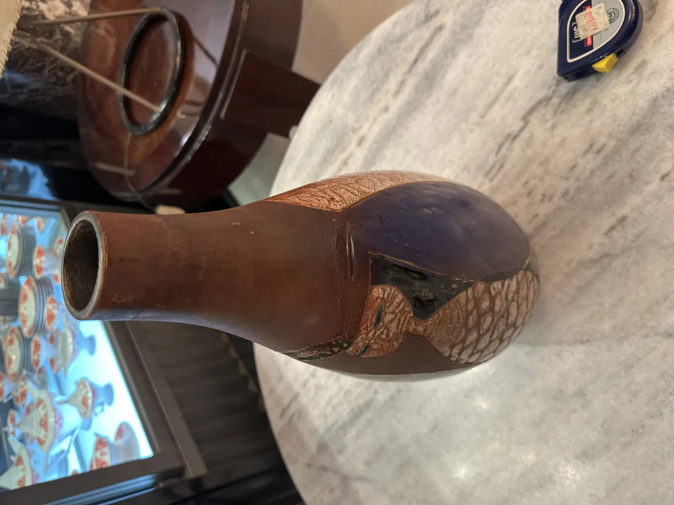 独特な形とさまざまな色合いを持つ古い陶器が、大理石のテーブルの上に置かれています。