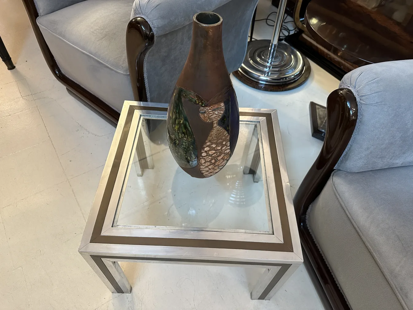 Antiga cerâmica decorativa em tons de marrom e verde com design artístico em frente a um sofá