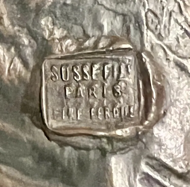 Metalldetail der Skulptur mit sichtbarer Signatur