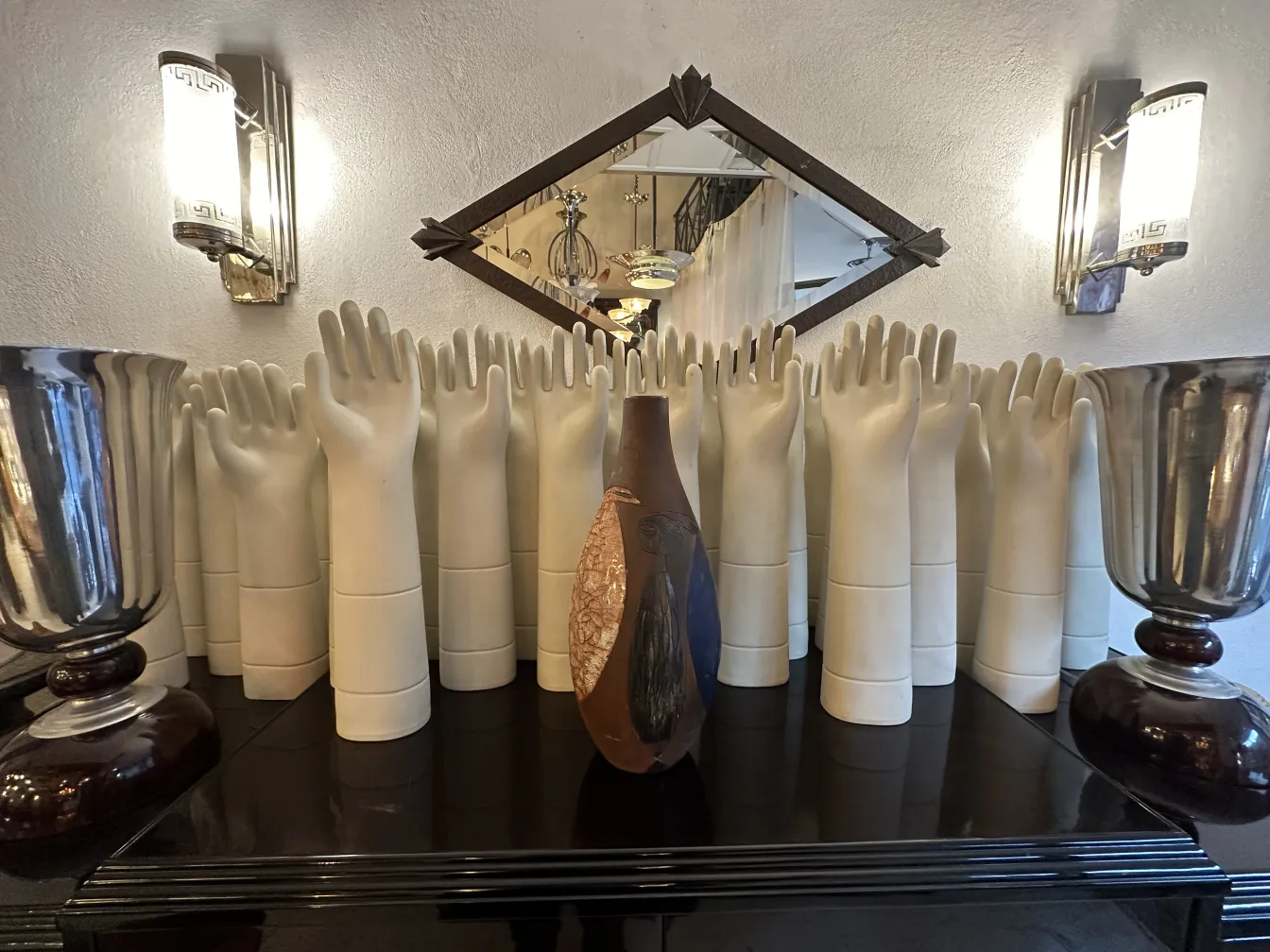 Cerâmica decorativa antiga em várias formas e cores, cercada por mãos brancas