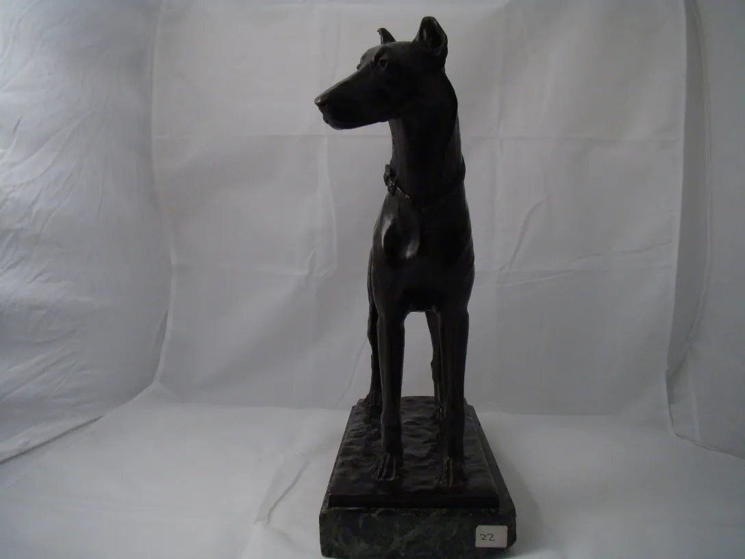 Escultura antiga de um cachorro preto em pé.