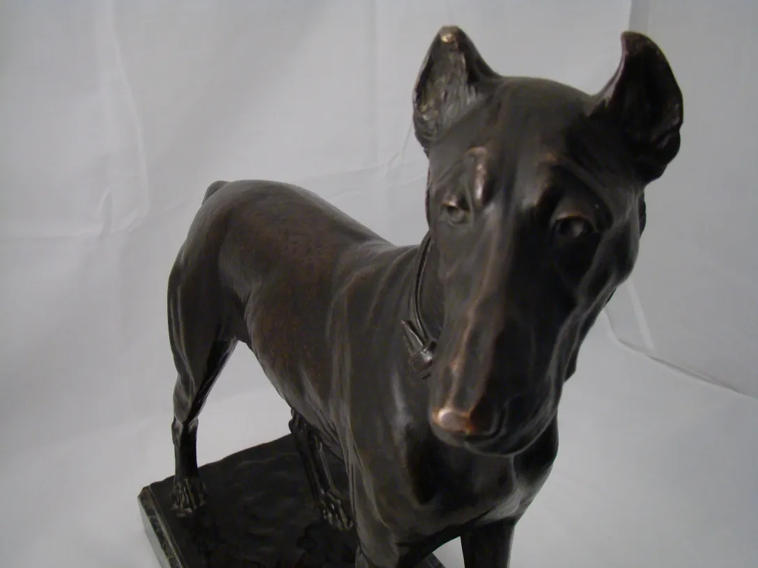 Scultura di cane antica in colore scuro con dettagli realistici.