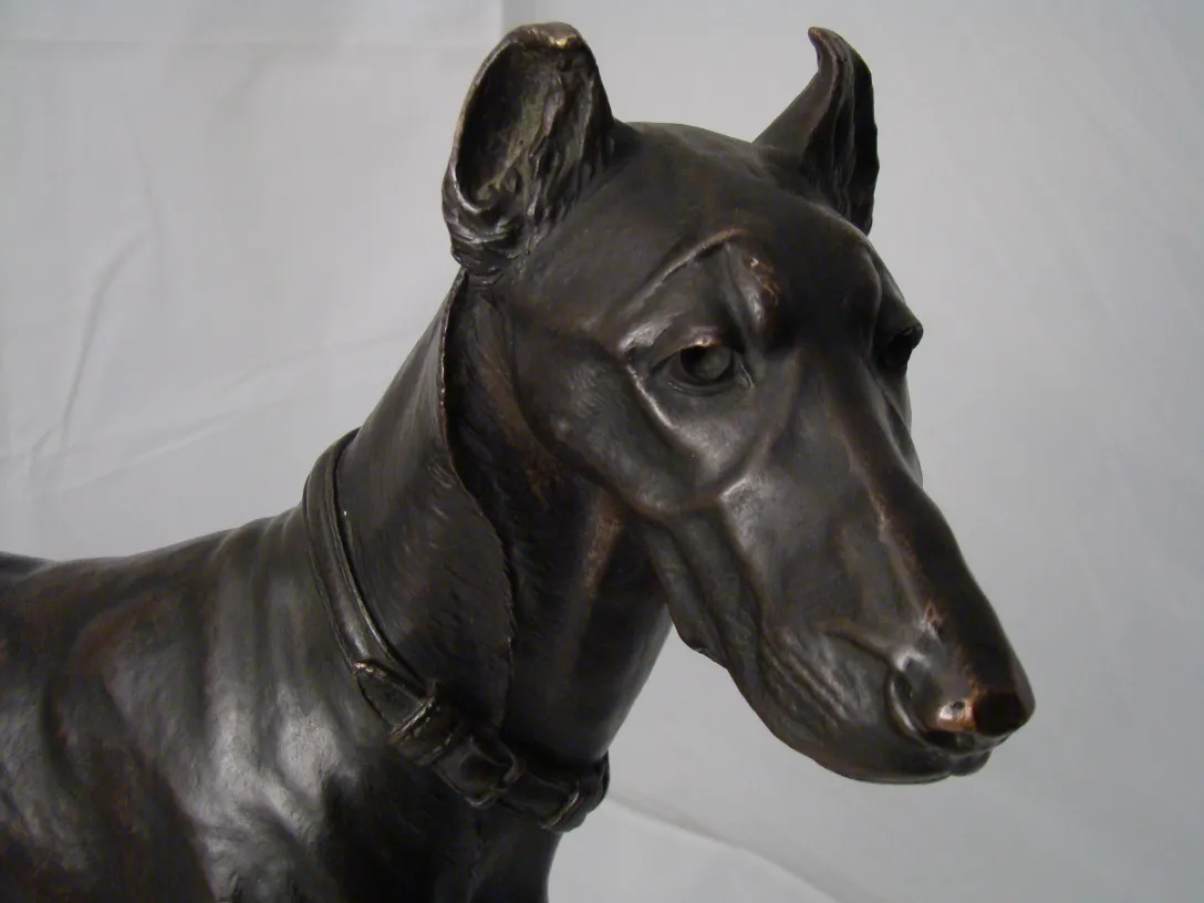 escultura antiga que representa a cabeça de um cachorro, com detalhes intricados no colar e expressão realista