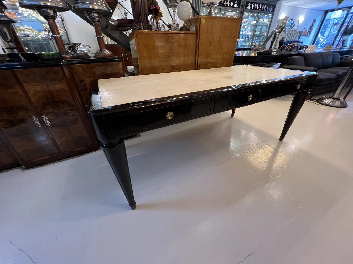 bureau ancien noir avec un plateau clair et des tiroirs dorés