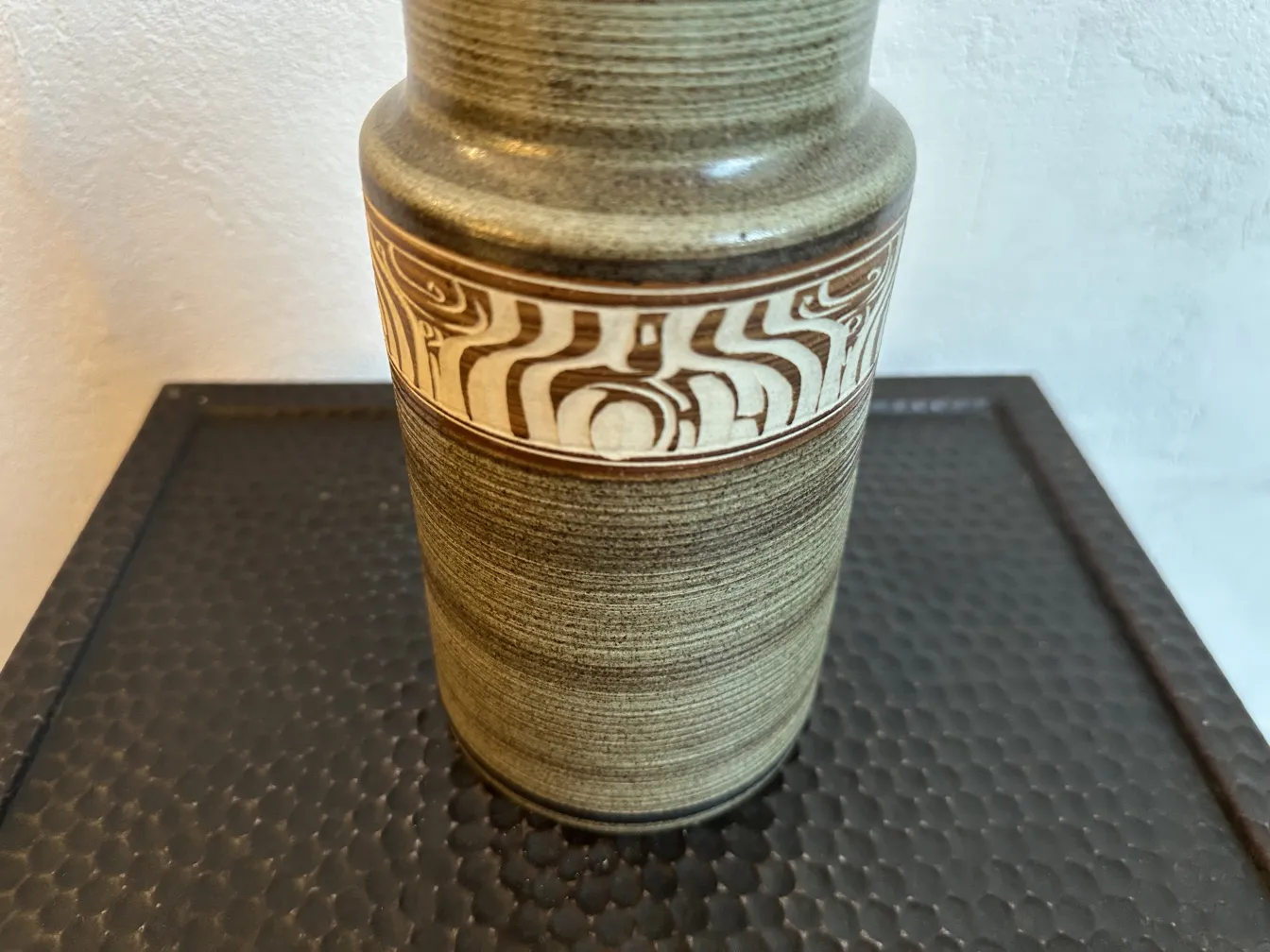 Antike Keramikvase mit markanter Dekoration in der Mitte.