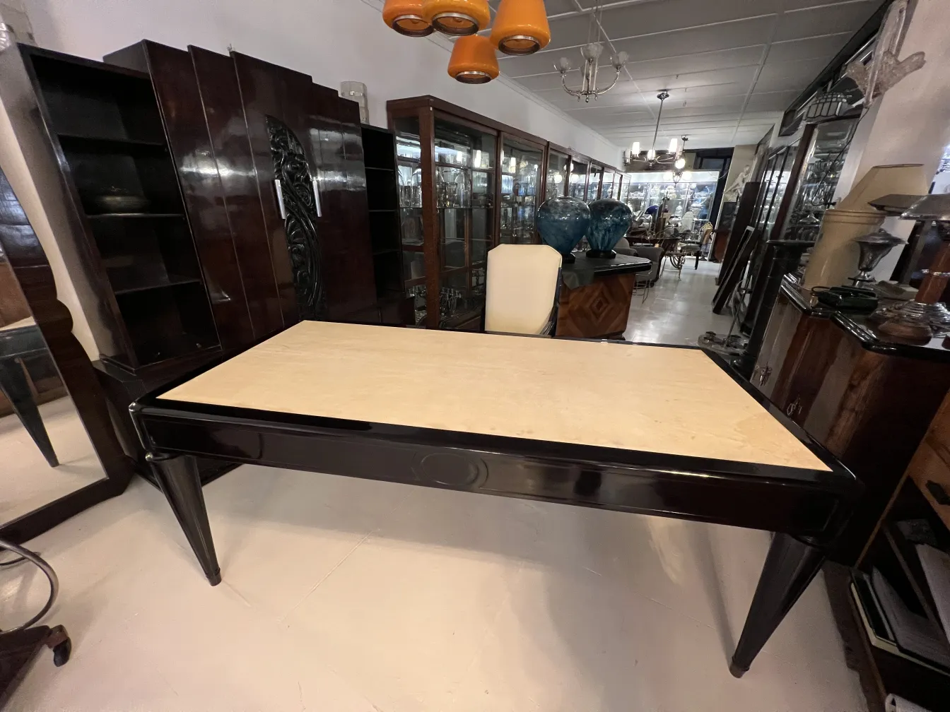 Escritorio antigo com superfície clara em um ambiente com armários e decoração.