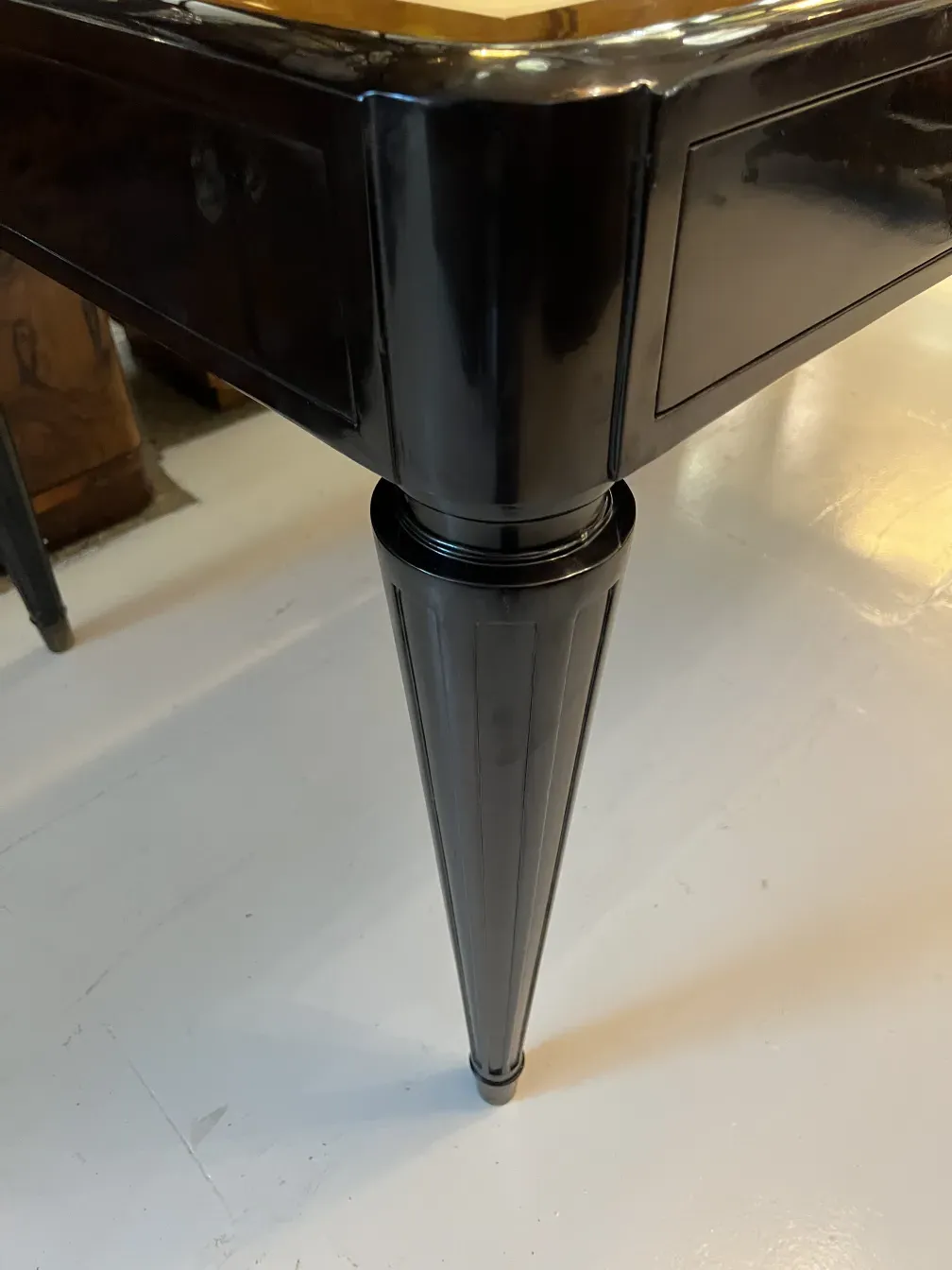 Détail d'un bureau ancien avec un design élégant et une jambe stylisée.