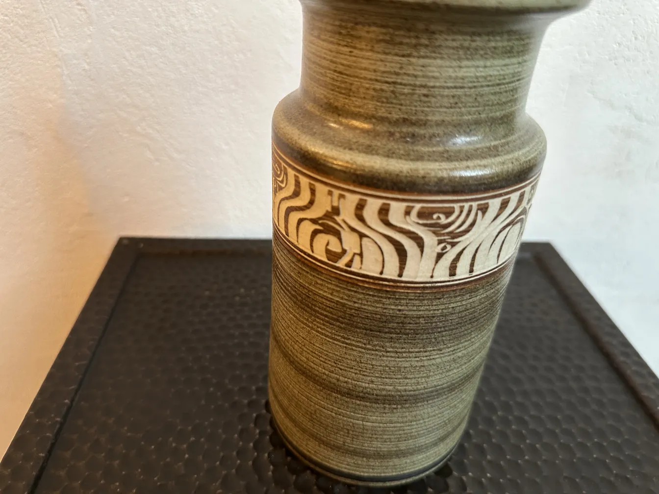 Vaso de cerâmica antiga com padrões únicos em um fundo neutro.