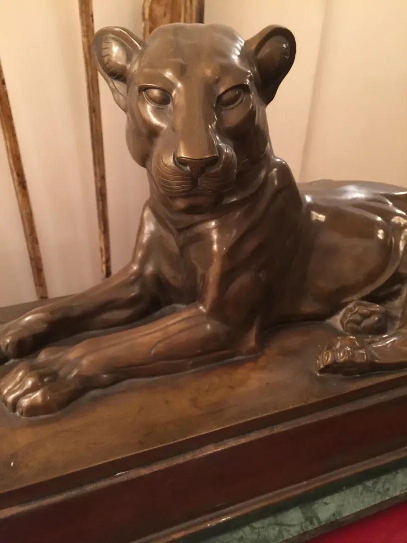 escultura antiga de leoa com expressão serena em um ambiente clássico