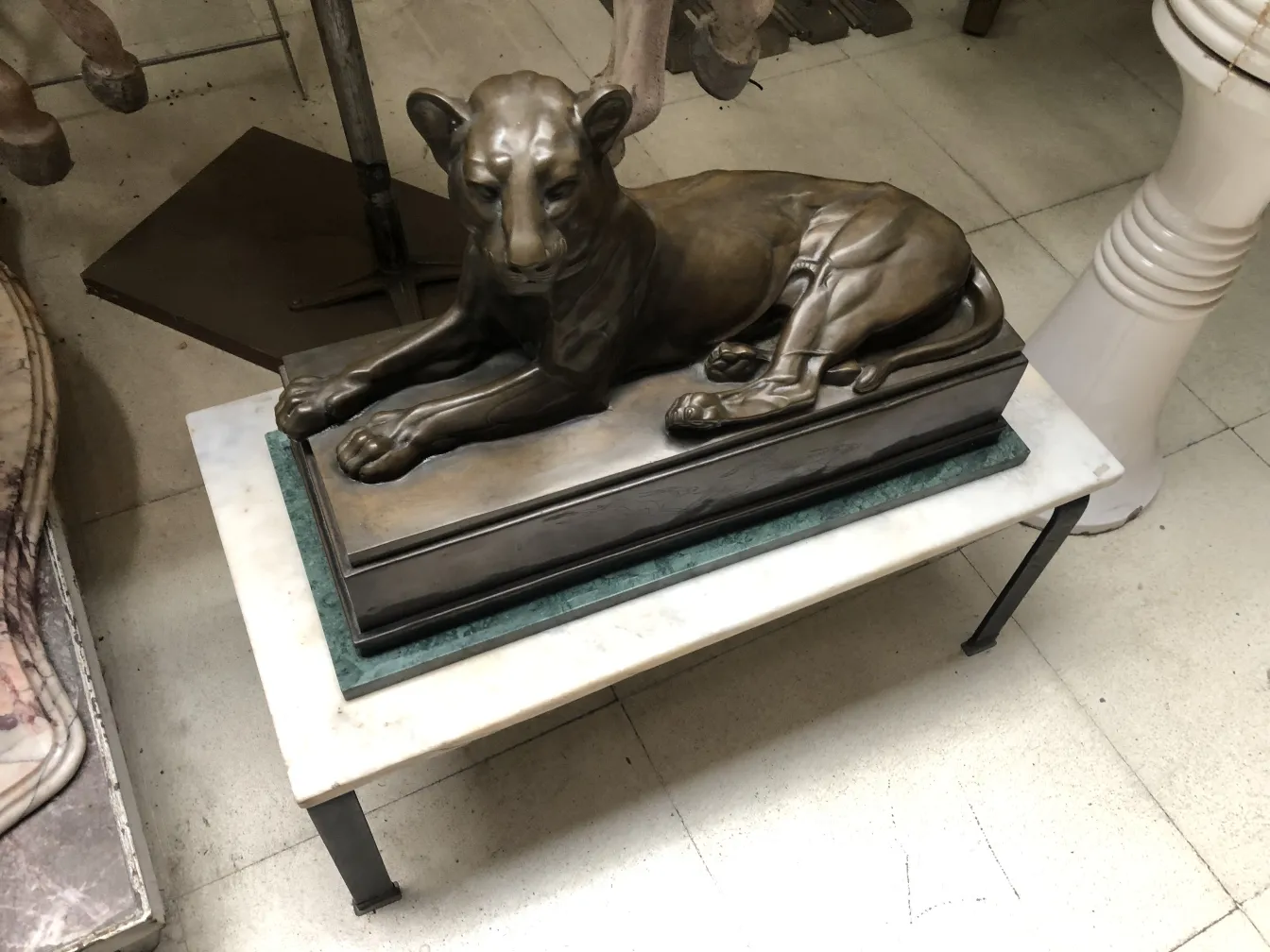 escultura antiga de leão em pose relaxada sobre a base