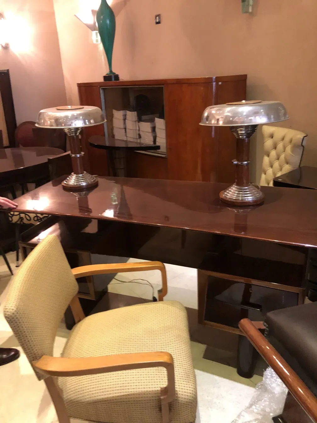 Vista de um escritório antigo com lâmpadas prateadas e cadeiras em um ambiente elegante.