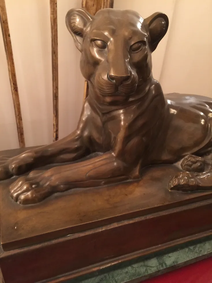 escultura antiga de leão em repouso em uma base