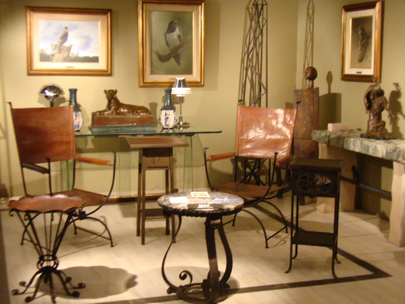 antique sculpture beside chairs and paintings on wall