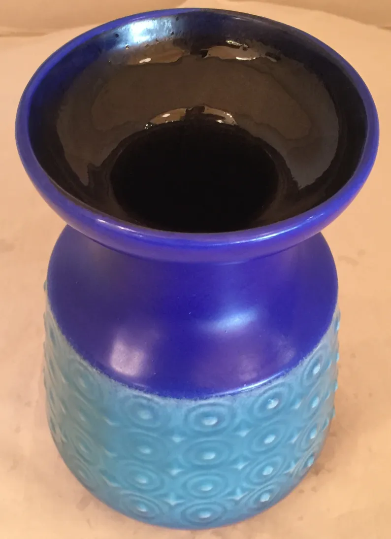 Antigua cerámica presenta un vaso azul con acabado brillante y detalles texturizados.