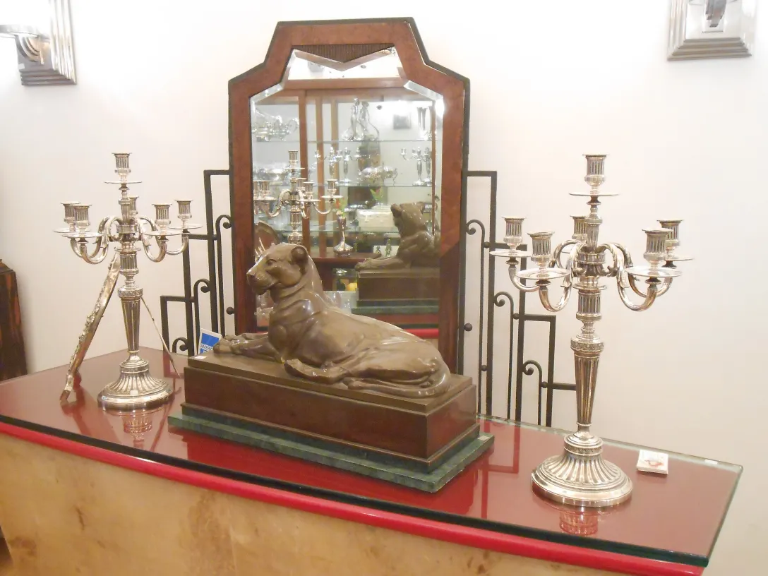 escultura antiga de um cachorro em repouso com candelabros