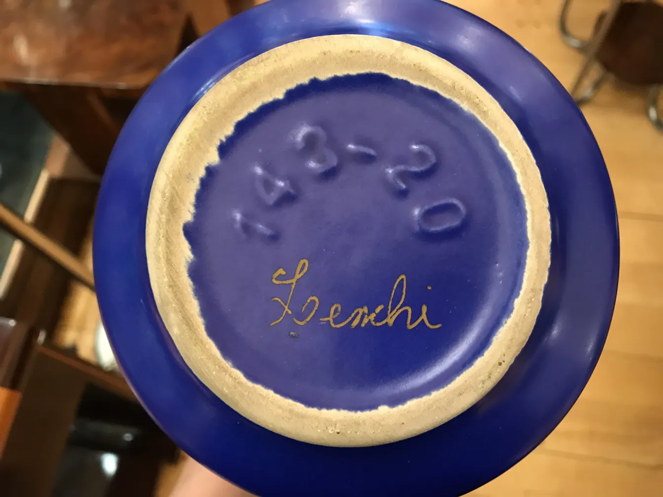 Objeto de cerâmica antiga com base azul, detalhes dourados e assinatura visíveis.