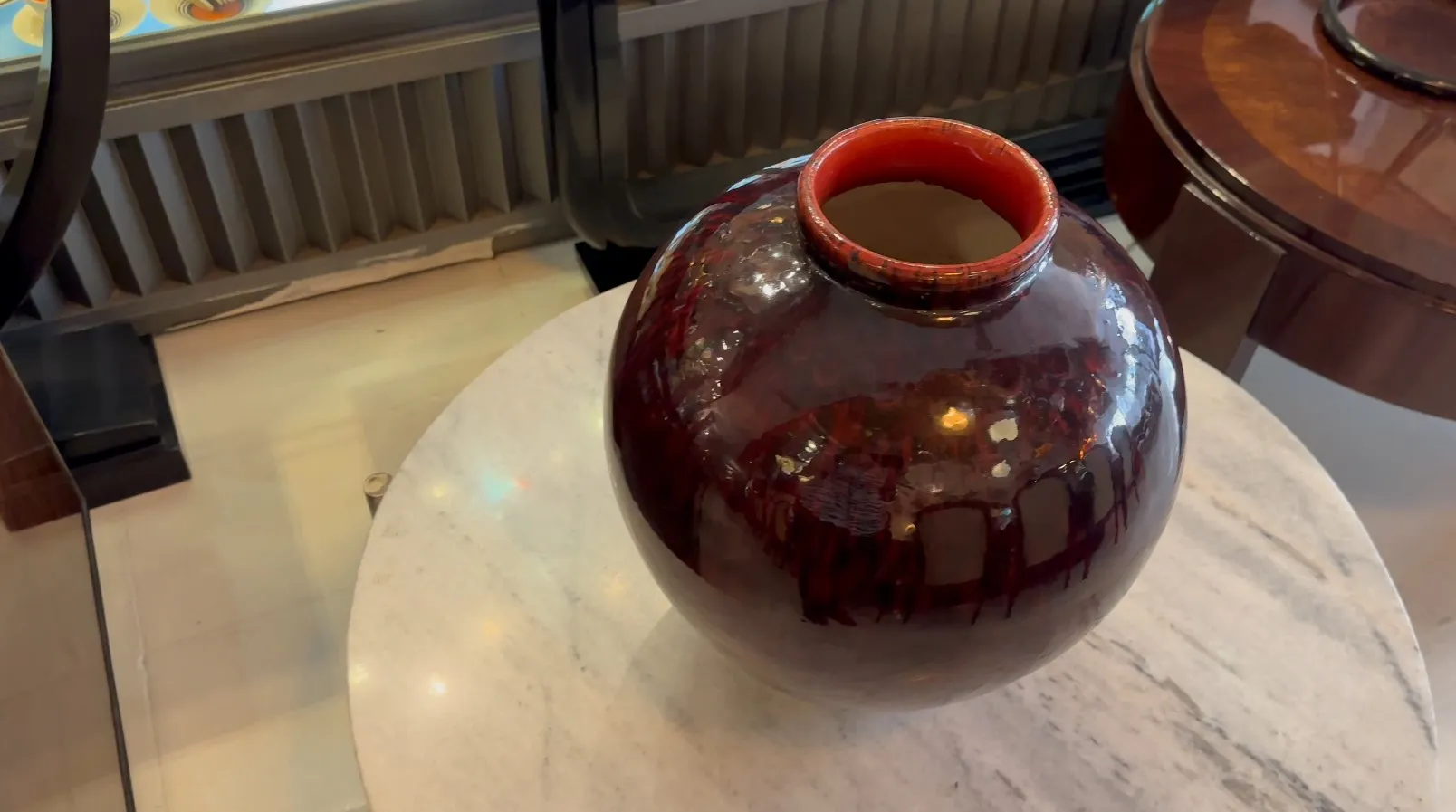 Ancienne céramique décorative rouge sur une table blanche, avec une finition brillante.