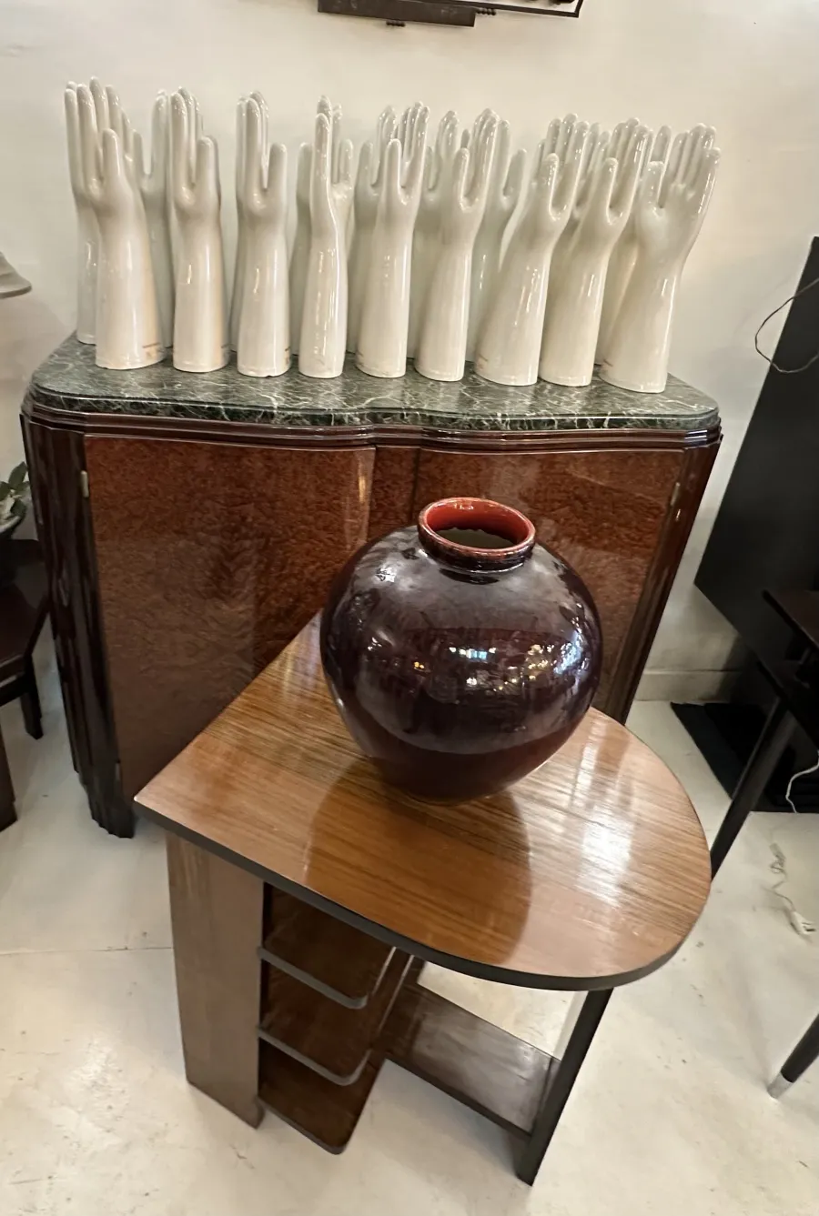 Antiga jarra de cerâmica escura em uma mesa triangular, rodeada por decorações