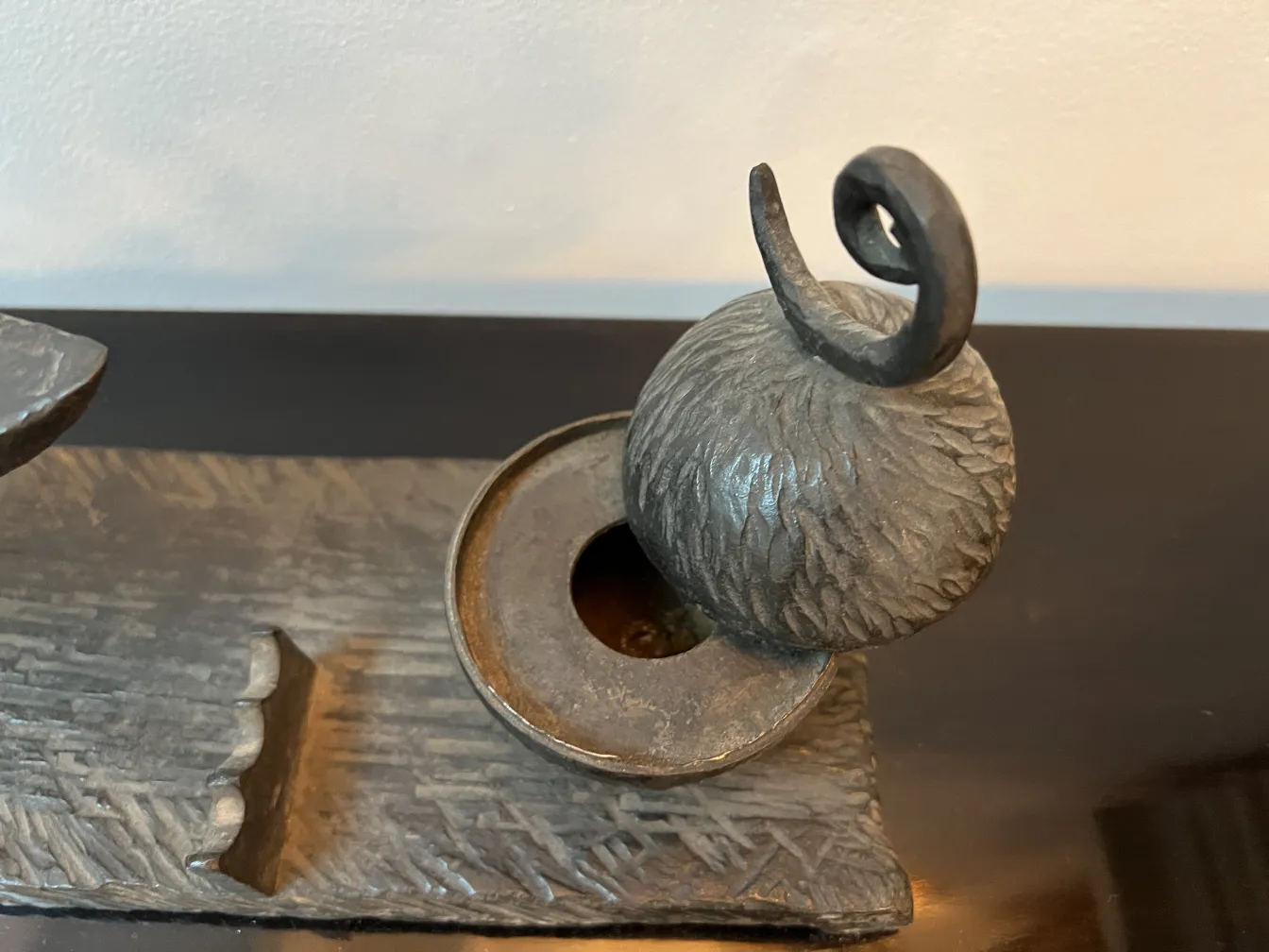 Antique sculpture with round shape and curved details on decorative base.