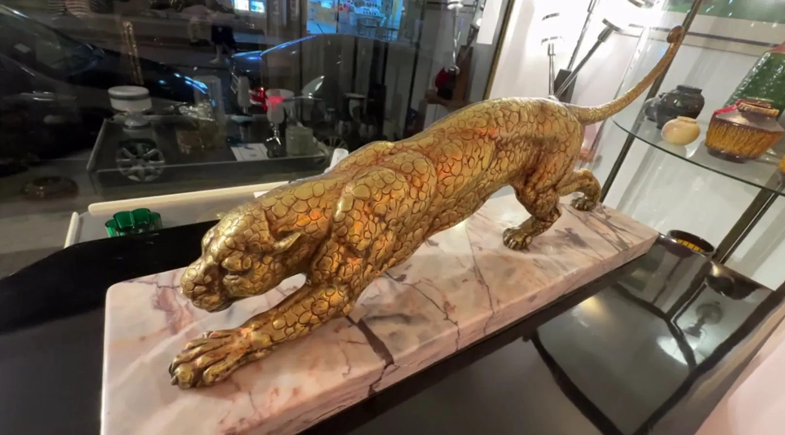 escultura antigua de un felino dorado, ambiente moderno y escaparate
