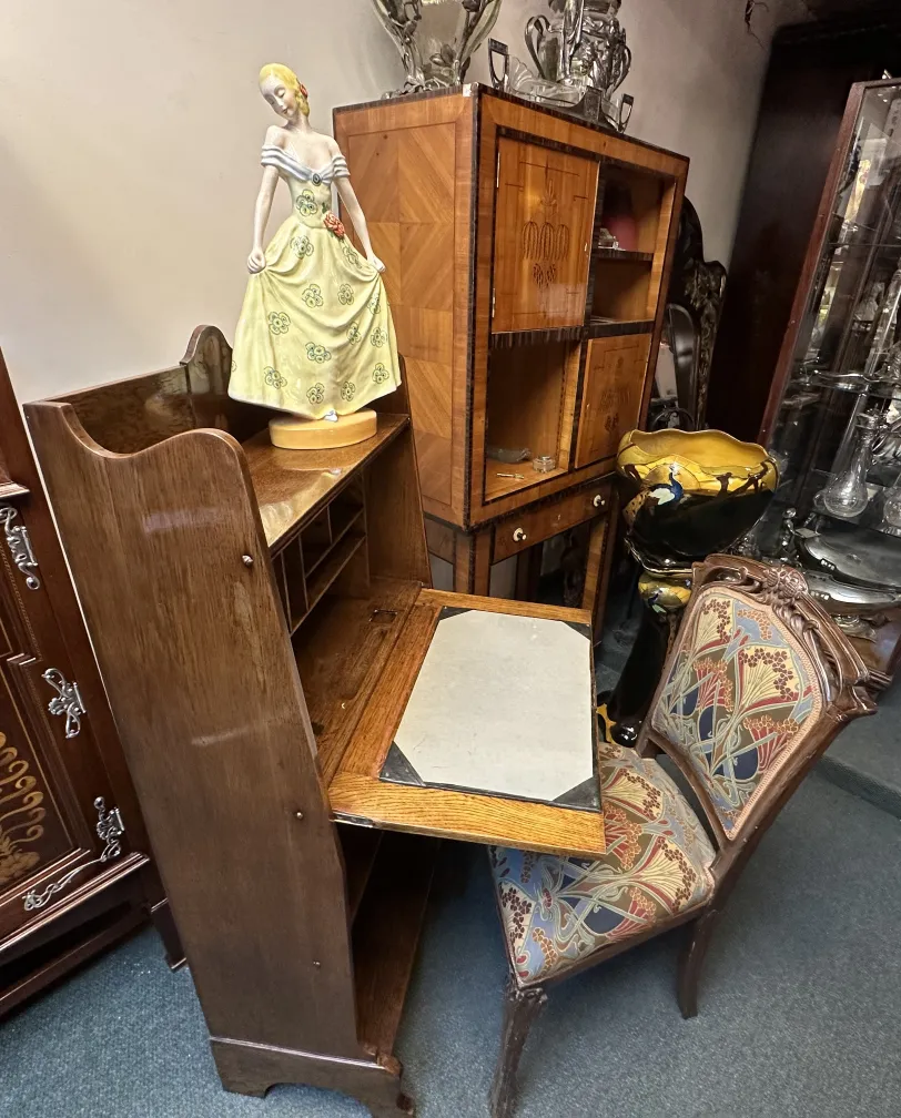 Bureau ancien avec étagère, orné et élégant, à côté d'une figurine