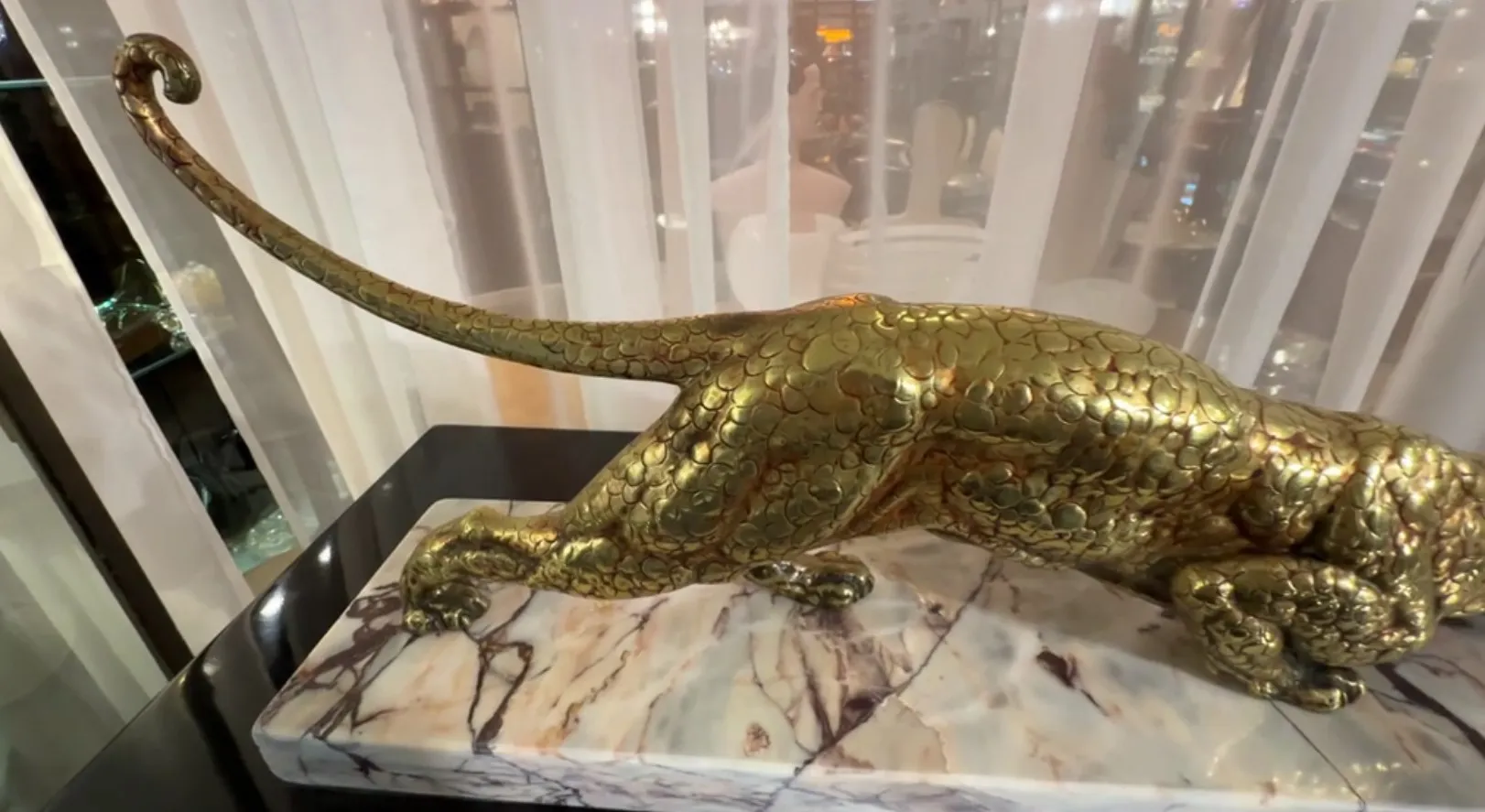 sculpture antique d'un félin doré sur une base en marbre, élégante et sophistiquée