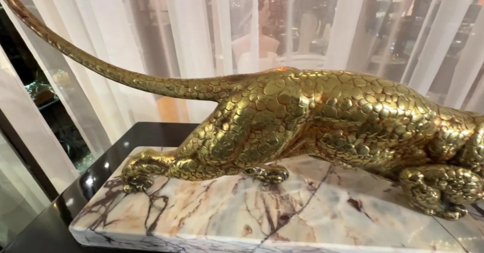 escultura antiga de animal com detalhes dourados e base elegante