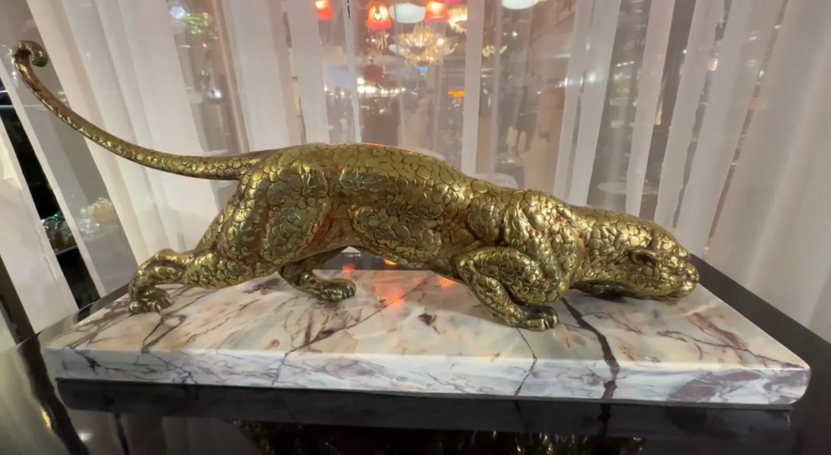 scultura antica di un felino in posizione di attacco, dorata