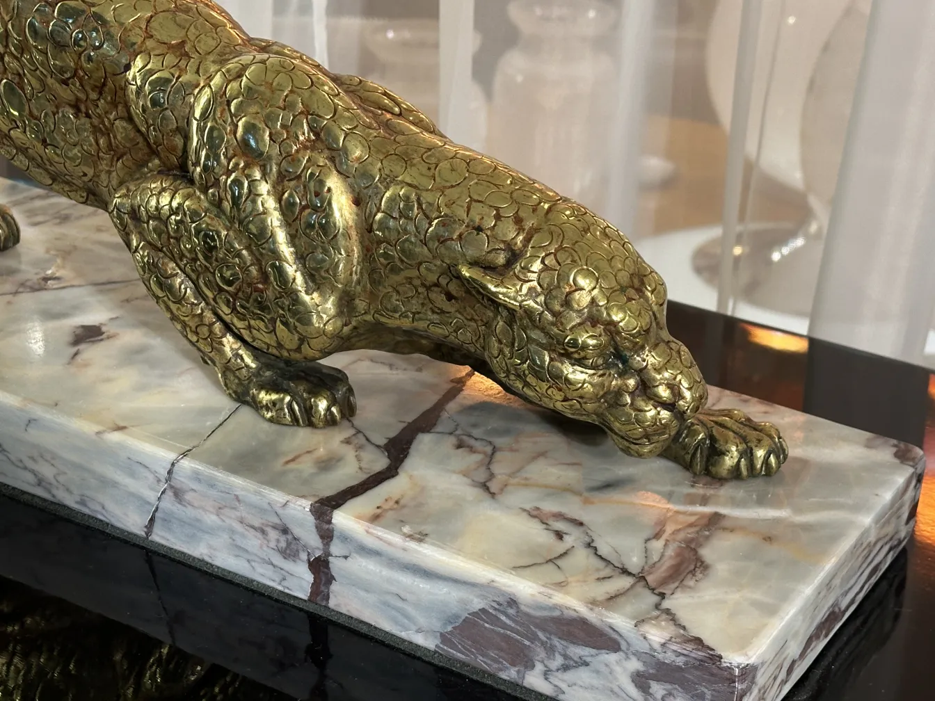 scultura antica di felino dorato su base in marmo