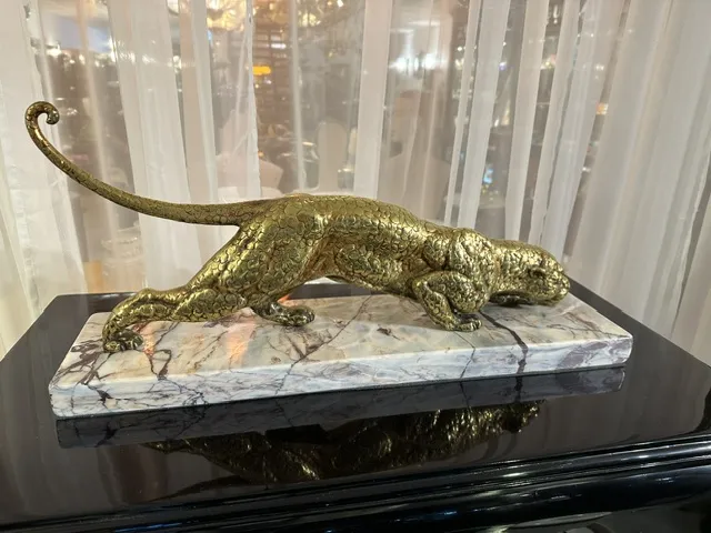 antique sculpture of a feline in dynamic pose on a base