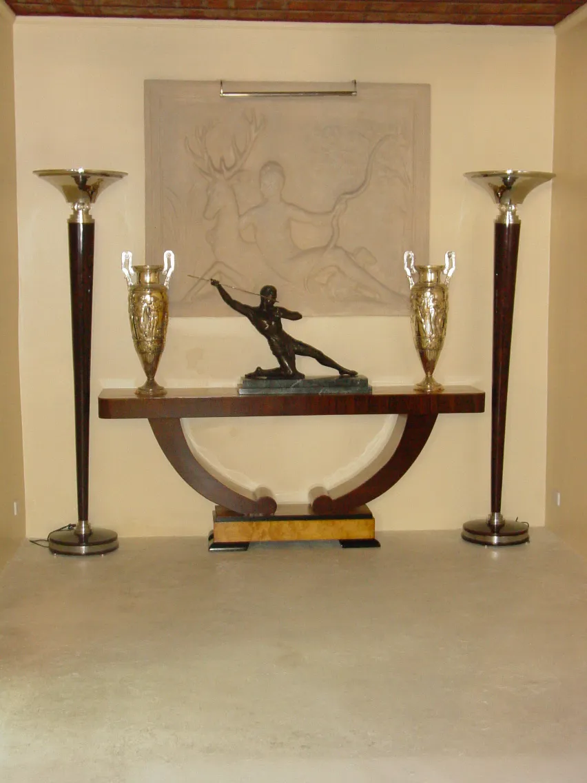 scultura nera in evidenza su un tavolo con vasi dorati