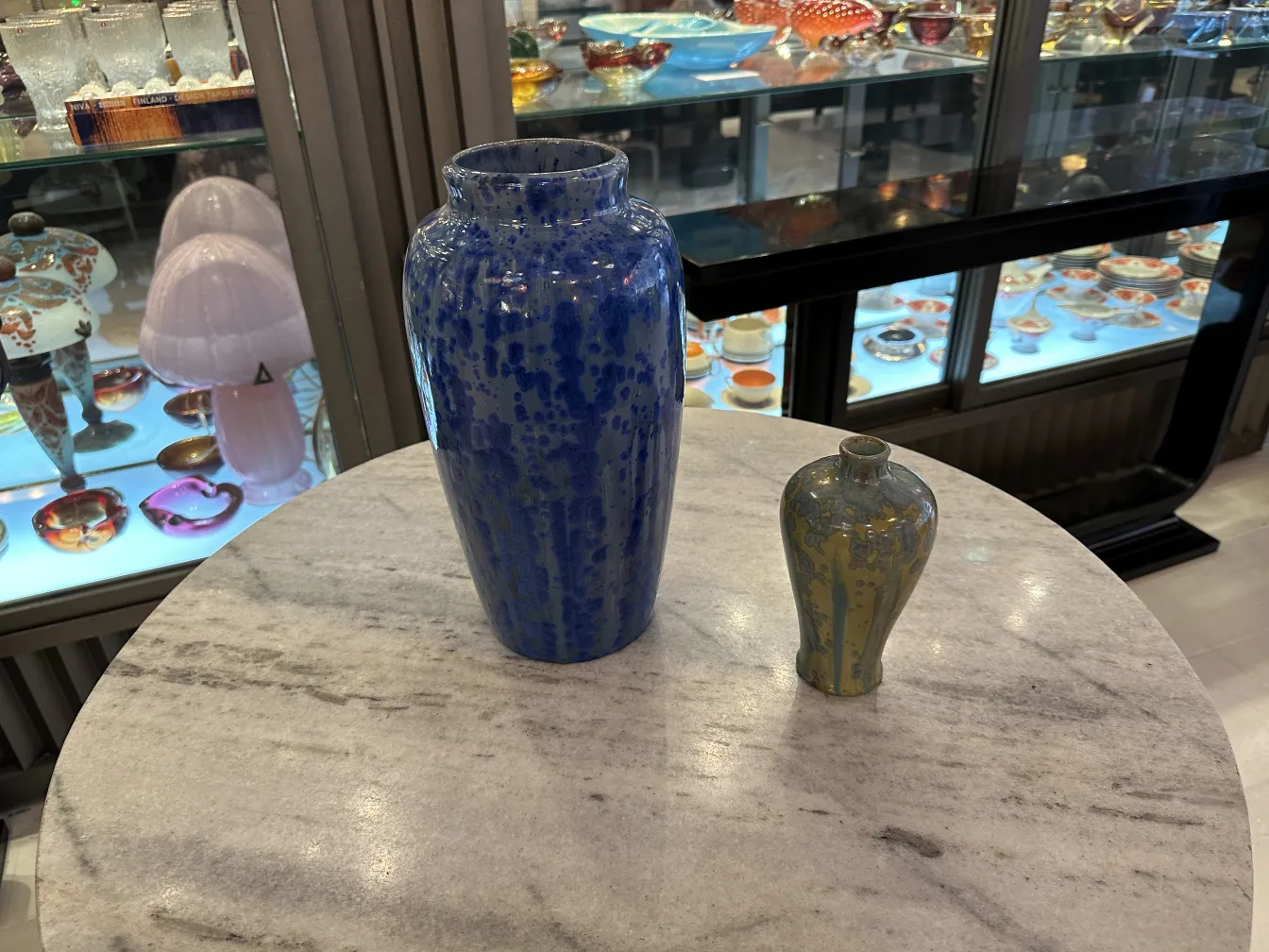 Vases en céramique bleus et verts sur une table en marbre dans un cadre ancien.