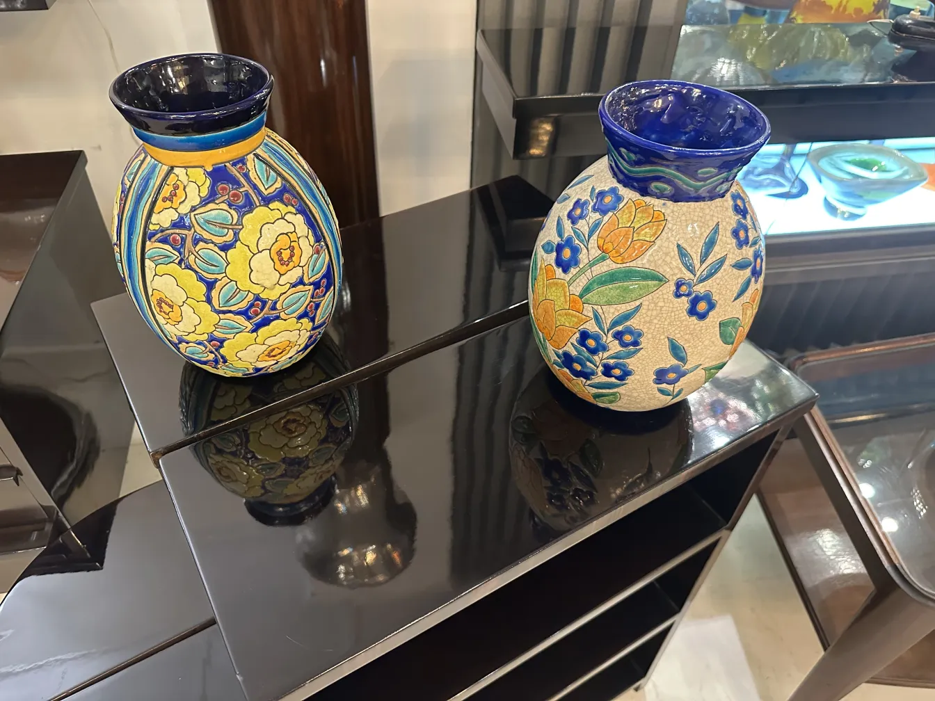 dois vasos de cerâmica antiga com padrões florais coloridos, decorativos, em um fundo contemporâneo